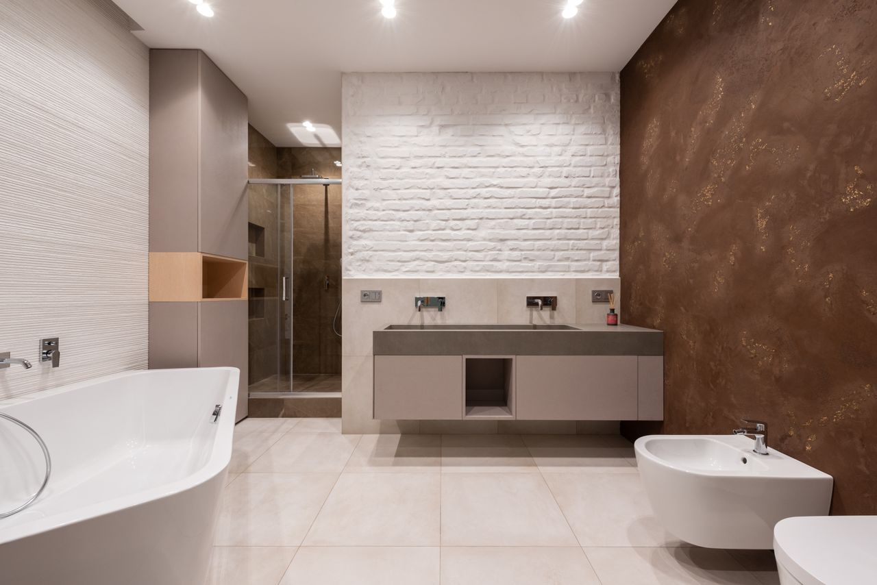 our-experience Interior of modern light bathroom with bidet and toilet in front of bath and cabinet with sink and faucet next to shower