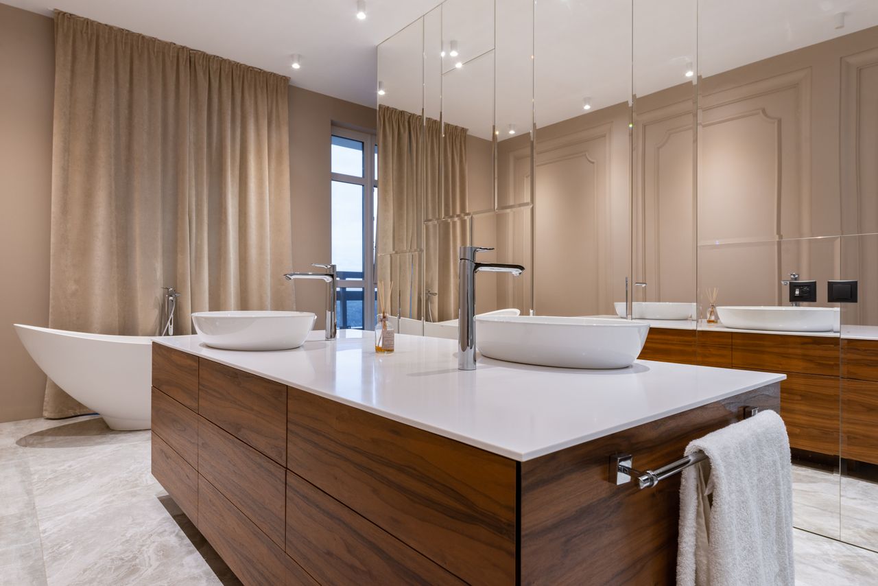 services-03 Minimalistic interior of modern bathroom with white sink and bath and mirrored cabinet in apartment in daytime